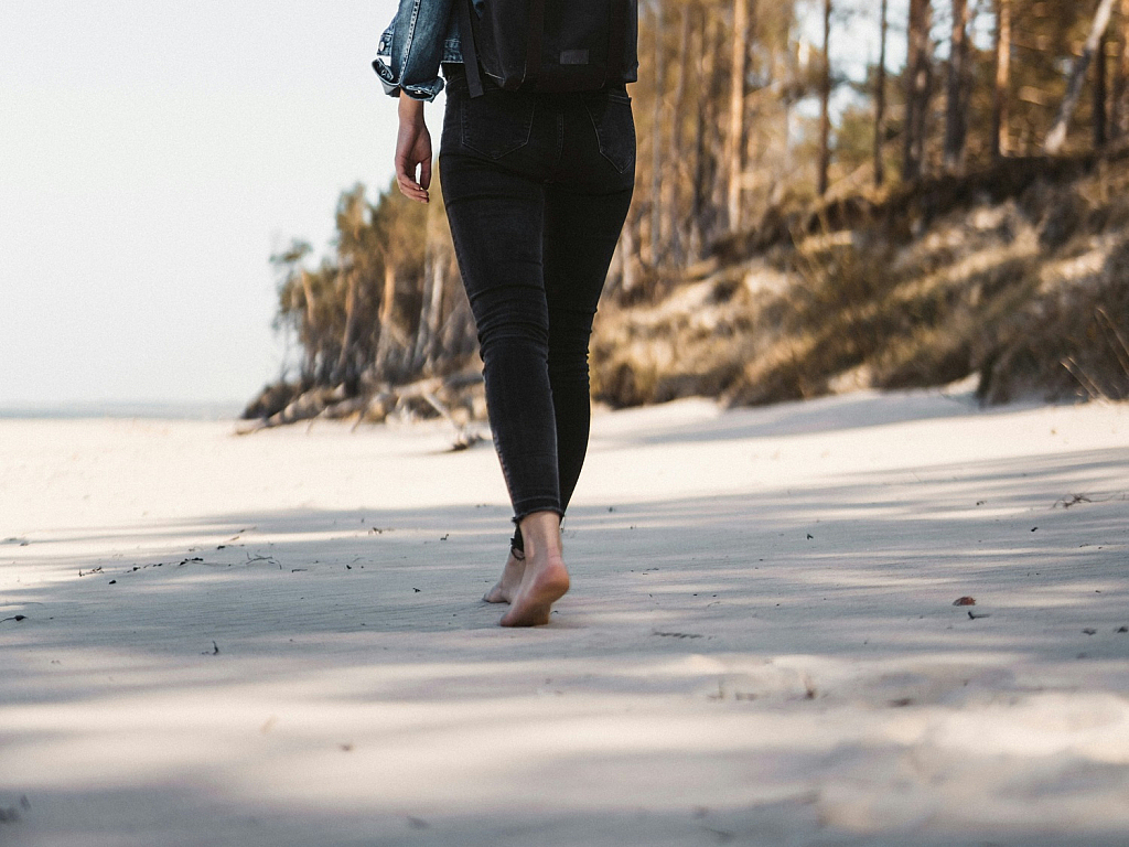 Woman wearing black skinny jeans barefoot on the beach - barefoot shoes review - Lookforsmile.com